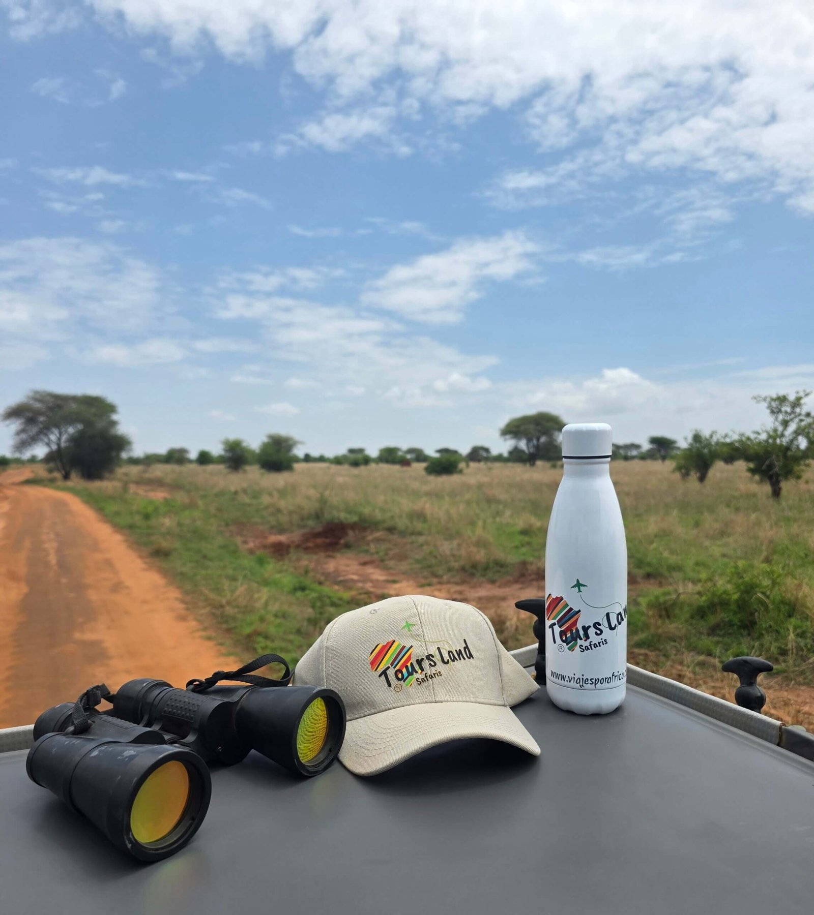 Gorra y botella de Tours Land Safaris sobre el techo de un jeep durante safari en Tanzania